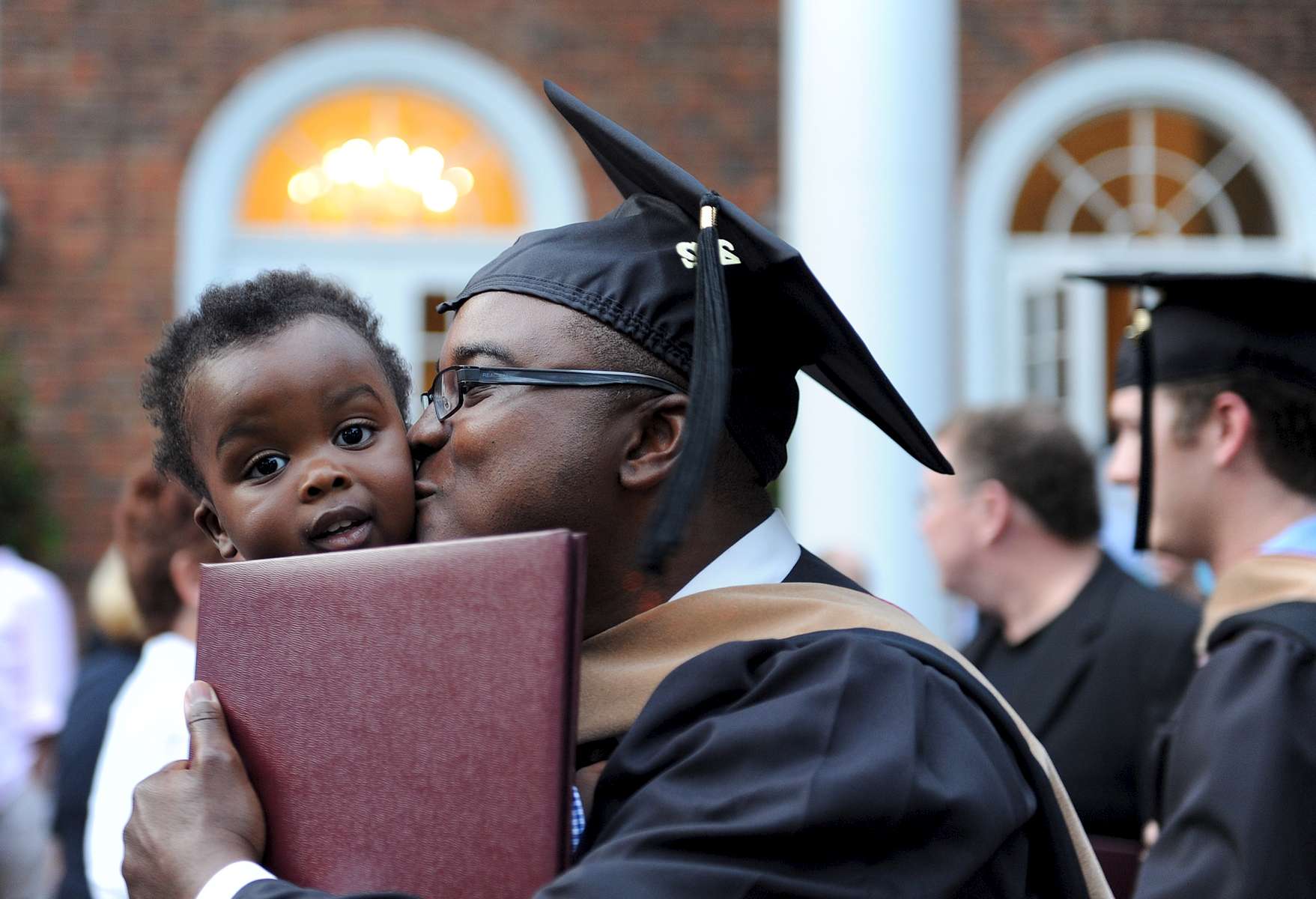A graduate of Elon's MBA program is greeted by his son after leaving the ceremony.