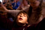 With her mother Terri pressed to her back, 7-year-old Amber Sturgeon's teeth chatter as she raises her arms in worship at River Valley Apostolic Worship Center in Middleport, Ohio. The Apostolic faith, an offshoot of the larger Pentecostal movement, is common within Appalachia. The movement's conservative views reflect the area's political atmosphere.