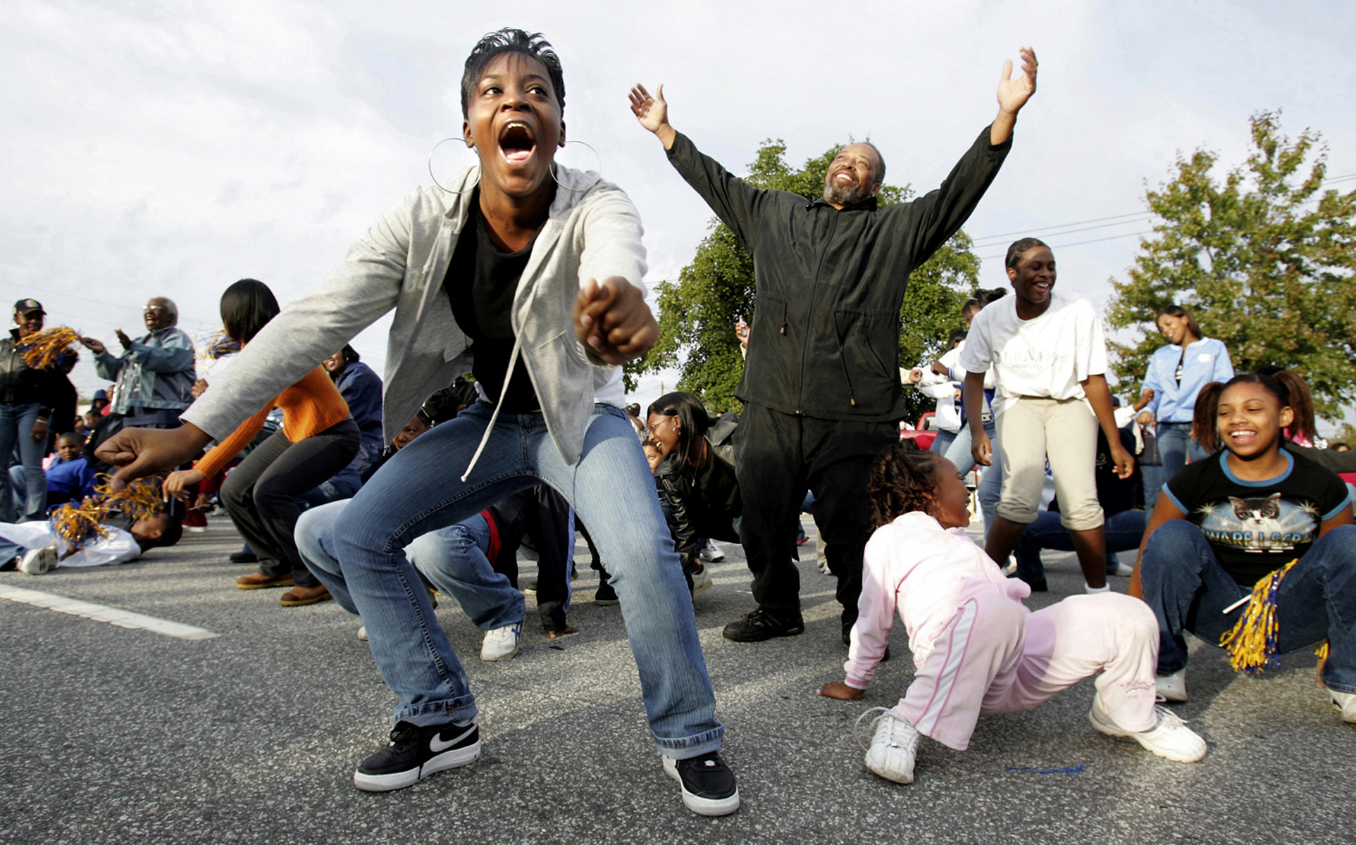 Brittany Davis and Len McCollum (arms raised) dance to the Cha-Cha Slide in an attempt to win free football game tickets before the A&T Homecoming Parade in downtown Greensboro, N.C.