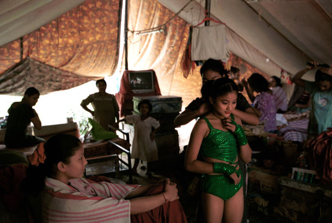 A Nepali contortionist prepares with other girls in their sleeping quarters behind the big top before an afternoon show in a rural community west of Delhi, India .