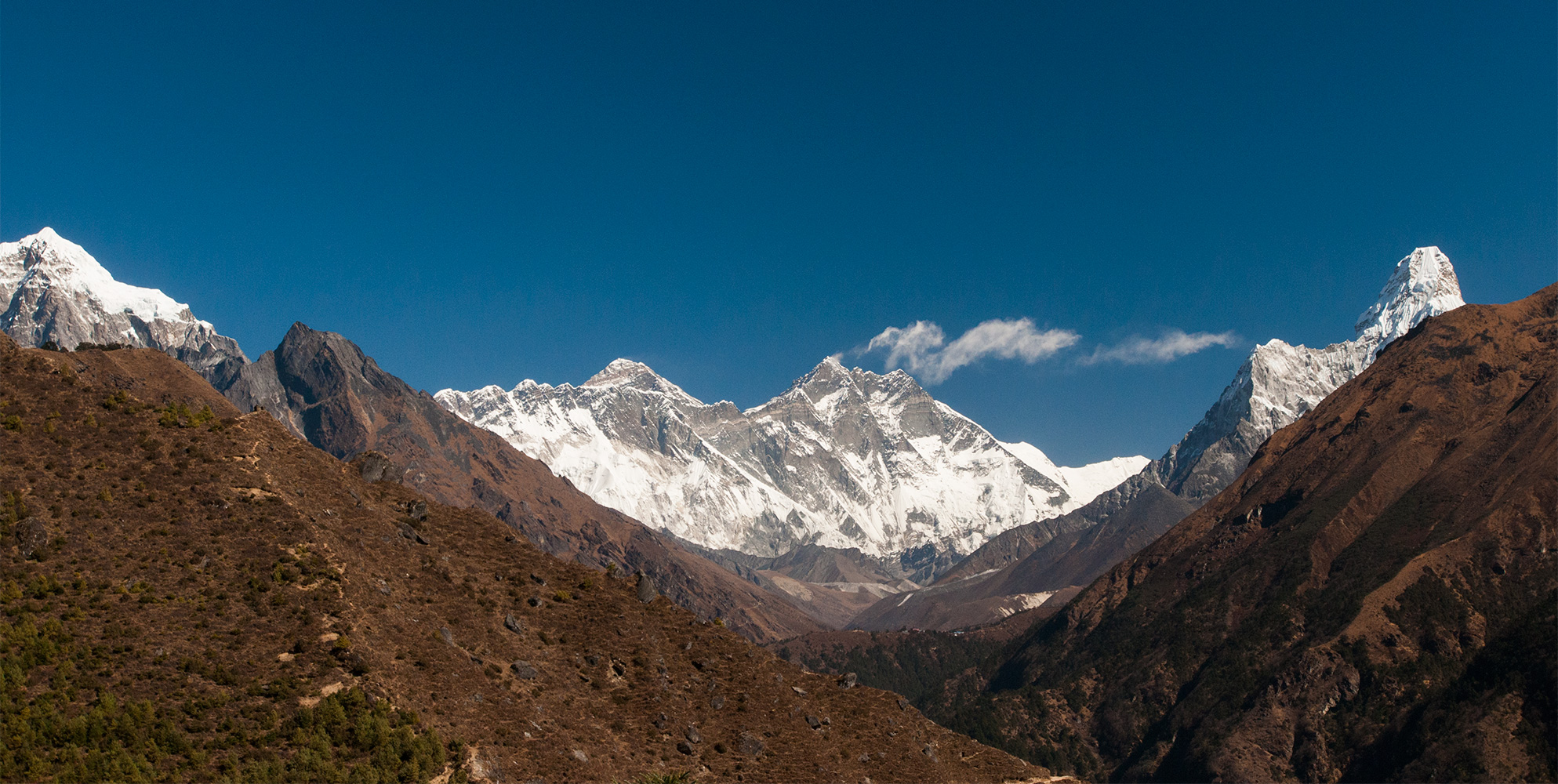 A view up valley from just above Namche Bazaar. Straight ahead, Everest peeps over the towering south wall of Lhotse, on the right is Ama Dablam, and on a low ridge in the middle distance is Tengboche Gompa.Nikon D300, 17-35mm. November 2008