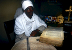 Kessis Dessaleng Simeneh of the Ethiopian Orthodox Church shows us the priceless Kebra Negast. This is a 13th Century re-write of {quote}The Laws of the Kings{quote}, which traces the lineage of the Kings of Ethiopia from the Biblical Solomon, and on it rested the authority of the Ethiopian monarchs. Written in Amharic on sheepskin, this is the only copy in Ethiopia today. It was one of two taken by Lord Kitchener when he invaded. In 1892, Emporer Johannes of Ethiopia petitioned Queen Victoria for their return (a copy of the petition, in Amharic, is also on the desk). The other is still in the British Museum in London.Nikon F5, 17-35mm, Fuji Velvia 100