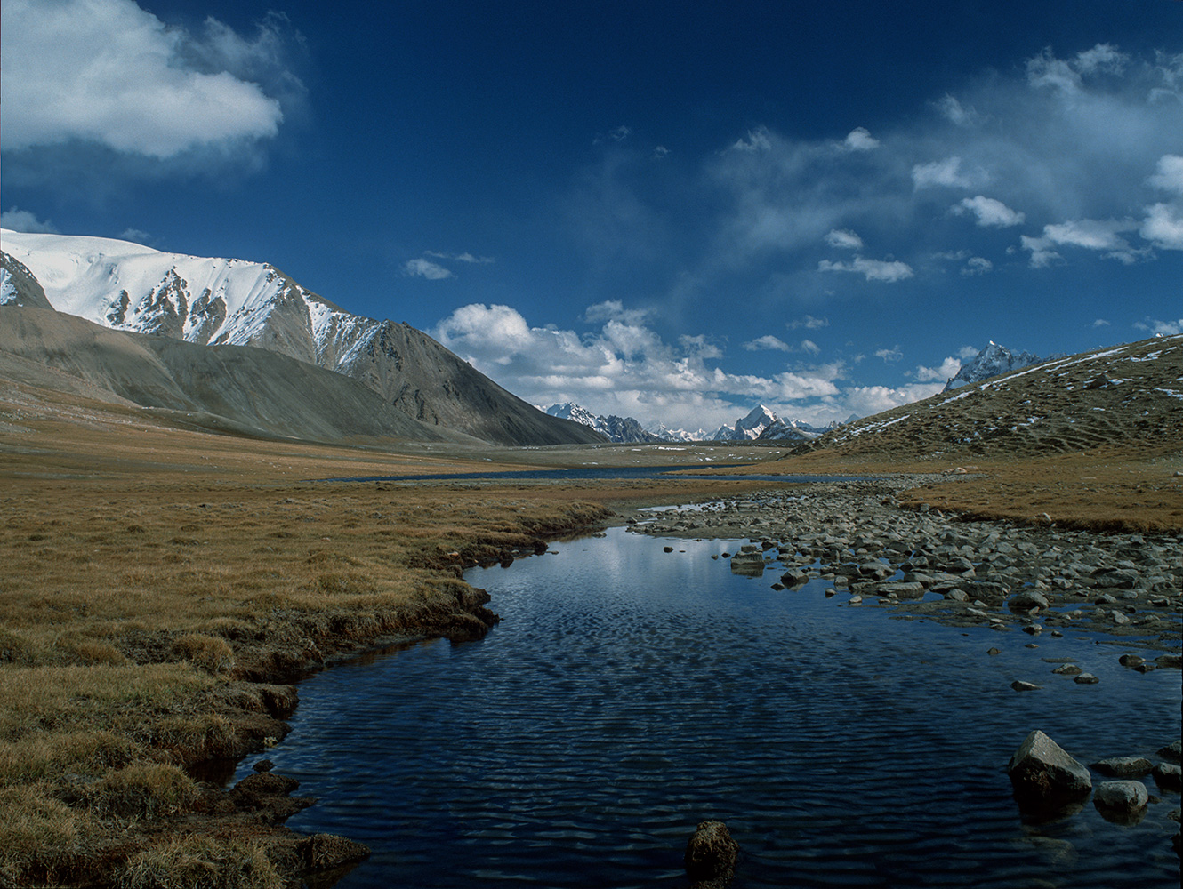 A view east across the Shimshal Pass from the top of Abdullah Khan Maidan. This legendary pass, first crossed by Younghusband in 1889 and then by Shipton in 1937, lies on the great Karakoram watershed. Rivers from the north-east side flow to oblivion in the Taklamakan desert in Xinjiang, whilst rivers from the south-west flow into the Indus and thence to the sea near Karachi....