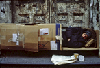 Homeless man sleeping in a cardboard box.