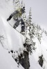   Derek Root grabs his tail as he drops over a cliff at Island Lake Lodge, Fernie, BC.