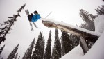   Jordan Sinnott grabs some snowy lumber as he airs past a tipped over tree stump.