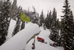   Derek Root gets inverted while pulling off a grab over a tree stump as Island Lake Lodge's Pisten Bully Cats pass in the distance.