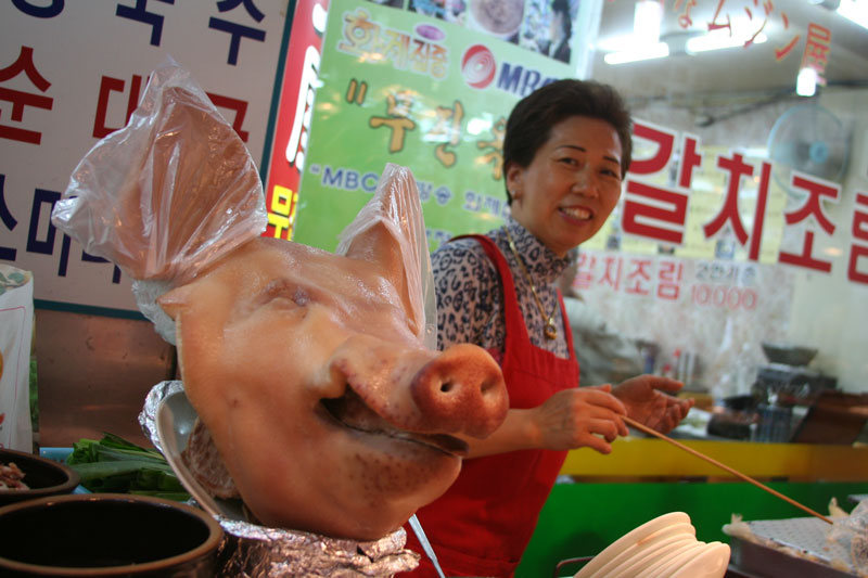 A pig head is on display as a vendor looks over at a market in Seoul.