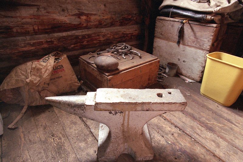 An anvil sits on the floor in a tack room.