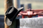 A cowboy hat and shades sit on a fence rail.