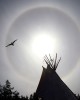 A bird soars above a tepee as a sundog graces the northern sky while Aboriginal Day festivities take place in Yellowknife, NWT, Canada.