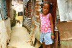 A young girl in front of her home in the La Lata neighborhood, on the banks of the Ozama River in Santo Domingo.  The area contains more than 200 squatter houses with as many as ten people in each house.  Homes are cobbled together with rusted pieces of metal, and have no plumbing.  Raw sewage runs through the streets, and the neighborhood frequently floods when the river rises.© Habitat for Humanity International/Ezra Millstein