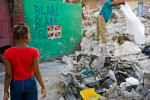 A young girl watches as a dead body is covered with a sheet, after being discovered decomposing in a pile of rubble three weeks after the January 12th earthquake. © Habitat for Humanity International/Ezra Millstein