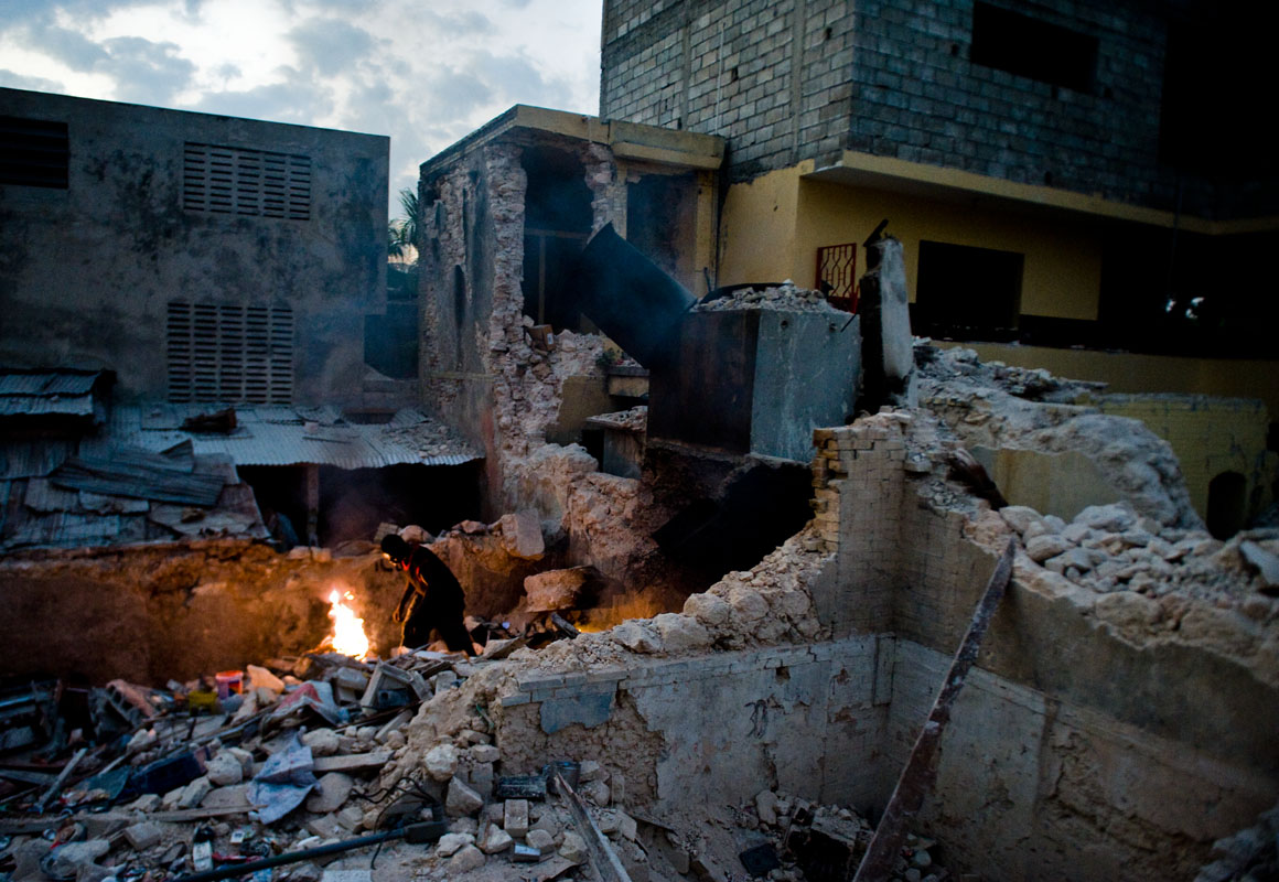 A man burns body parts among the ruins of a collapsed building, three weeks after the January 12th earthquake.  © Habitat for Humanity International/Ezra Millstein