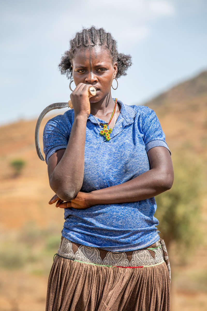 Otitte, 24, cuts grass on a steep hillside near Ale. Mercy Corps is working with villagers to protect their land so they have enough grass to feed their cattle and survive the dry season.As drought becomes worse, rangeland like this becomes more precious to keep cattle healthy. Mercy Corps is helping villagers protect their land so they can sell cattle at a profit to survive the worsening dry season.