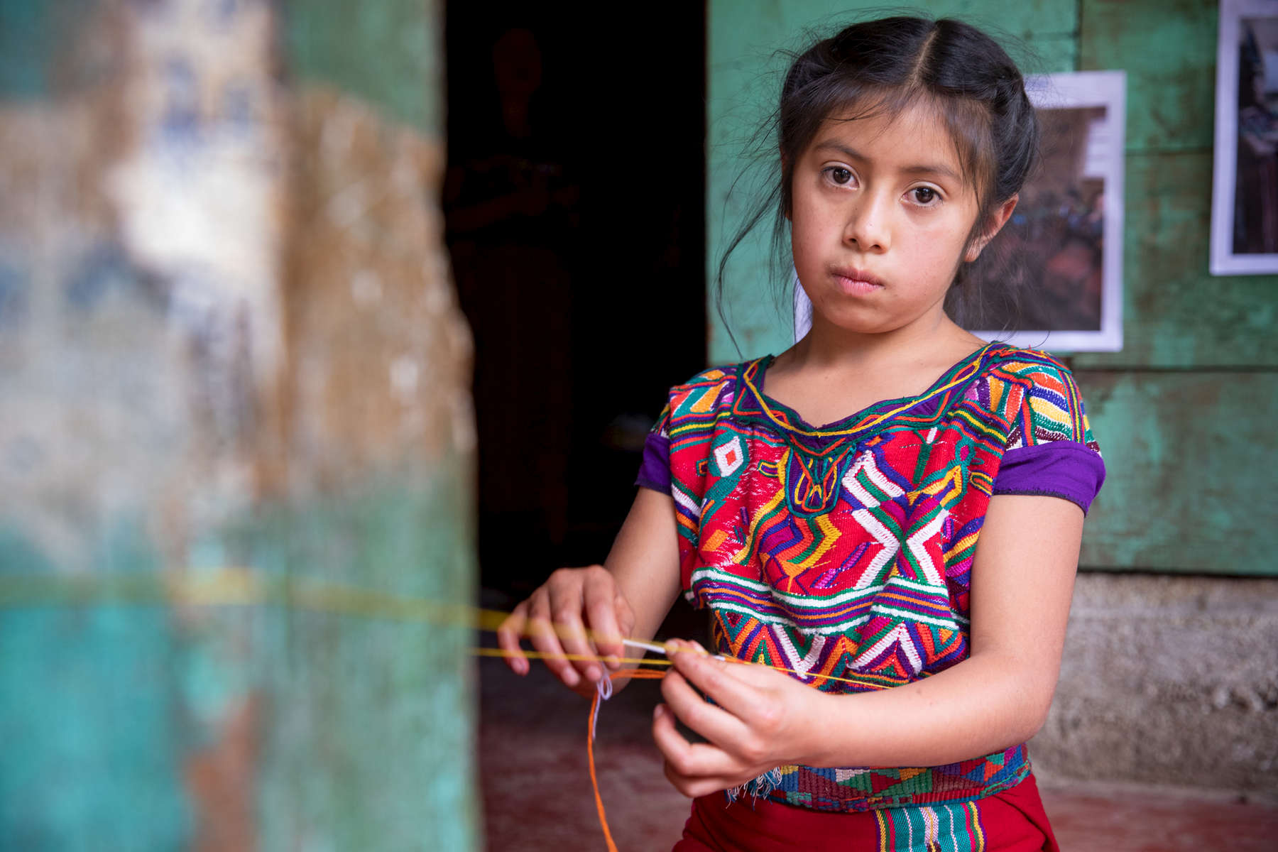 Heidy, 9, weaves on front of her family's home in a small community in Guatemala’s Western Highlands. It is an agricultural region characterized by underdevelopment, malnutrition, poverty and a lack of opportunity. Her grandmother, Maria de León Santiago, recently started saving for the first time ever through the “Communities Leading Development” program, which is implemented by local partners with technical support from Mercy Corps. The program aims to improve quality of life for families in 200 communities in the Western Highlands, in part by installing community savings and loans groups to build financial stability. Maria is the president of her savings and loan group, and she says she is focused solely on saving right now, so she can give her family a better life than she had growing up. 