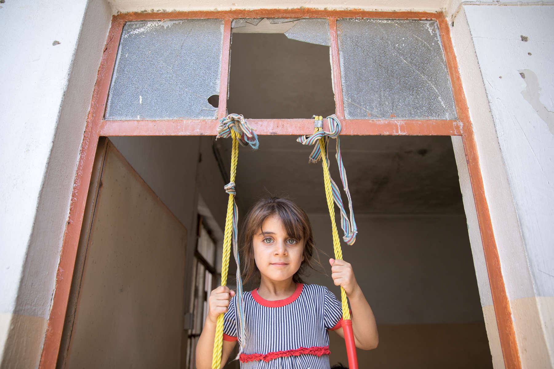 Shahad Moatez Hashem, 5, plays on an improvised swing. She lives with her grandmother, Faiza Abdulrazak Aziz. Faiza and her extended family fled from ISIS. There is nothing left at their house; their car was burned and their home was destroyed. They share a home with five families. She has six children, three boys and three girls, and six grandchildren living in the shared house.The family received a $400 cash distribution from Mercy Corps. Cash assistance is the quickest and most efficient way of helping because people can buy what they and their families need most. Since July 2016, Mercy Corps has helped more than 12,000 families impacted by conflict around Mosul.