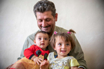 Ahmad, 51, holds his granddaughters Zinab, 2, and Bilasan, 6 months. They are Syrian refugees living in an informal tent settlement. They fled Syria in 2012 when a bomb destroyed their home. Since then, they have lived in a tent community with 23 other families, where Ahmad built a schoolhouse that teaches more than 40 Syrian kids.Ahmad was a farmer back in Syria, but when he saw how none of the children in this community could read or write, he decided to be their teacher. The walls of his classroom are covered in posters teaching English, Arabic, science and math, while the ceiling is decorated with recycled materials the children gathered. “I try to put hope for the children here. So I’m proud of what I did,” he says.More than 700,000 Syrian refugee children are out of school. Ahmad built this classroom so that when the time comes for the kids in his community to return to Syria, they’ll be ready to pick up their education again. “I built everything here by myself,” he says. “I started this to teach children here, because if I didn’t, they would take their own direction in their life and do the wrong thing, like drugs or going to the streets. Children in this generation are our future. Because of that, I started this school.”Ahmad’s school teaches children ranging from ages 5 to 13. They meet from 8 a.m. to noon, six days a week. At first there were no chairs, and the students sat on rocks in the sand. The community pulled together to help buy carpet, stools, and school materials. “It’s a benefit for everyone here,” he says.Ahmad uses Khabrona, a digital platform built by Mercy Corps and Cisco to help refugees access critical services through their cell phones. Once he used the app, he was able to get documentation for his son to live legally in the country. “I felt relief,” he says. “I felt like I was legal because I could go back and forth and my child could go back and forth …  This program really helped a lot of families.” Ahmad lives about 13 miles from the Syrian border—close enough to hear the sound of airstrikes in the distance. The sound is a reminder of the life he used to have and the struggles he’s endured for his family’s safety. “I used to own a farm, now I’m working for a farmer. I used to make people work for me and respect them, now I’m working for someone who doesn’t respect me,” he says. “It was really hard. We have a lot of depression.”Ahmad has a close relationship with the kids in his school, who call him Teacher or Uncle. When the kids hear the airstrikes, they often come to him to ask him to explain it. “Most of the children actually didn’t live this, so at first they didn’t know,” he says. “They thought it was fireworks. But after they go back to their parents and start to see the news, they come back to me and ask me about it, “We saw the news and people died and everything.” I tried to make the picture better, but you can’t. I tried, but it will stay a black picture because someone died.” 