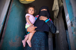 Maha, 34, holds her 1-year-old daughter Heba. They are Syrian refugees. Maha's husband Mohammad has worked on and off in Jordan for several years, but the war in Syria has made it his permanent home—his house in Syria has been burned down. When his wife followed as war closed in, she was placed in Jordan’s Azraq camp but fled after a few weeks. Together, they struggle to provide for their five children, who are out of school.Maha and Mohammad were separated by the war for more than two years. When they reunited, their daughter, Alala, didn’t recognize him. Today they live together in a small tent in Jordanian desert, trying to scrape together work until peace returns.A few of Maha and Mohammad’s kids are old enough to remember when war broke out in their town. “My daughter, when the plane came … she started to cry, because she saw, in front of us, the plane carrying out massacres of innocent people,” Maha says. In Syria, Mohammad and Maha were small farmers raising their kids in peace. But since war forced them from home, now they live as refugees, struggling to cope with what their family has been through. “I swear that when the night comes, and we hear the sound of planes, my body starts to shake out of fear for my sons,” Maha says.Mercy Corps connected the family to mobile banking, which they use to pay bills and save money on their phones. Their dream today is to continue on to Europe where their kids can continue their educations and live in peace. “I’ve suffered,” Mohammad says. “I don’t want them to suffer like me.”
