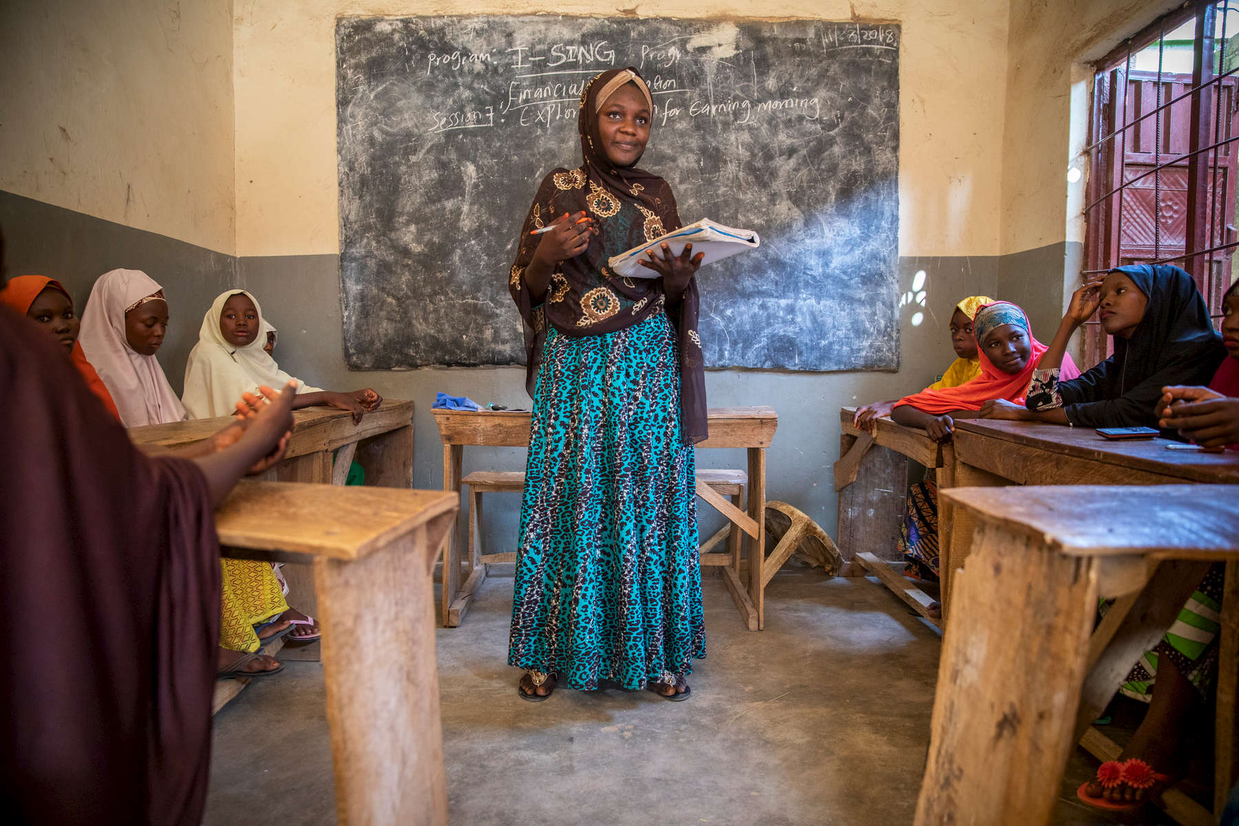 Suwaiba Yakubu Adam (18, brown hijab) teaches a group of 25 girls from her community who she identified and recruited herself. Using the same curriculum she learned from Mercy Corps, she guides lessons in everything from financial literacy to sexual health, believing sharing of this knowledge can be transformative for them. Suwaiba has been through a great deal in her 18 years: the death of both her parents, harassment by local gangs, attacks by Boko Haram. Yet she perseveres, stoic and determined, crediting her parents for instilling in her a desire to help people. After participating in Mercy Corps’ girls group in her community — part of the I-SING program, which provides life and vocational skills to vulnerable youth in Boko Haram-affected areas — Suwaiba felt so strongly that more girls should have the opportunity that she started leading her own group, independent of the Mercy Corps program.With the Boko Haram crisis behind her, she’s continuing to pursue to her own ambitions too: she wants to complete school and become a pharmacist, because it’s a way to serve her community. 