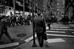 Man in a suit waits as the Occupy Wall Street protest passes on Wall Street. Protesters would march daily through side streets around Wall Street shouting {quote}Banks got bailed out and we got sold out{quote}  ©2017 Yunghi Kim/ Contact Press Images