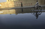 Graffiti marks the wall of an Iraqi police station in the center of Falluja before the two U.S. offensives against insurgents left the city in ruins. A broken city water pipe has flooded the street. 