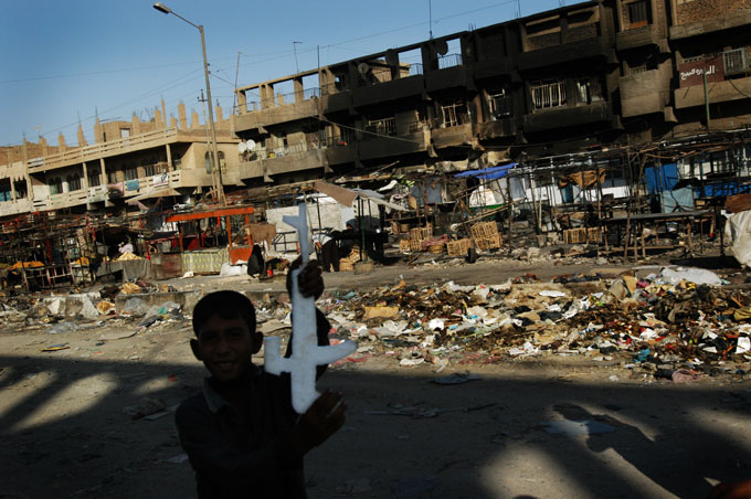 A boy brandishes a toy kalashnikov on a main thoroughfare food market the day after it was heavily damaged forces and the Mahdi Army. U.S. forces blasted the apartment from helicopter gunships. 