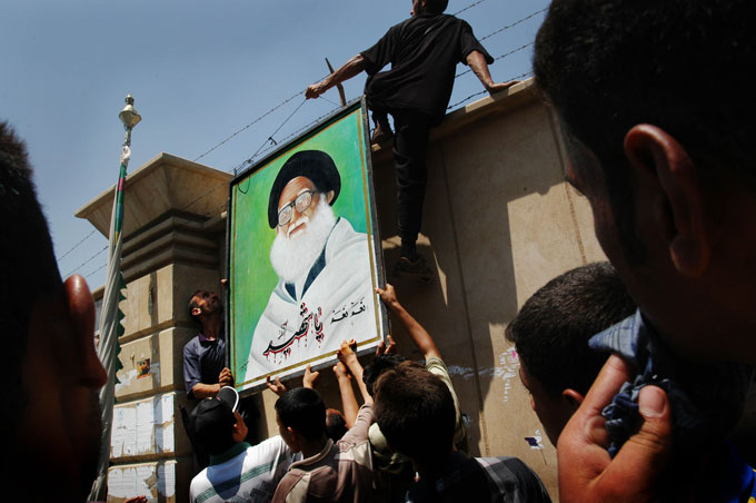 Demonstrators hang a picture of Muqtada al-Sadr’s uncle, Mohammed Bakr al-Sadr, a Shiite cleric who was assassinated for opposing Saddam Hussein, on a wall outside the green zone. The protest was in response to U.S. military actions against Muqtada al-Sadr and the Mahdi Army. Thousands of al-Sadr’s supporters participated, including some Iraqi police. 