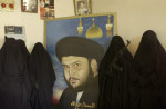 Followers of Muqtada al-Sadr pose with a portrait of their leader. The women assist the Mahdi Army by supplying the fighters with food and other support during battles with U.S. forces. They say they are willing to fight for the militia if the need arises. 