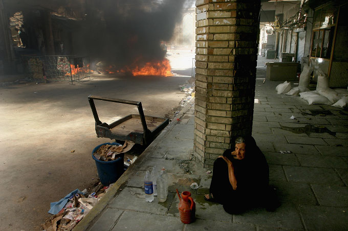 An elderly woman sits in the street 50 meters away from the shrine of Imam Ali in Najaf shortly after an intense battle between U.S. forces and Mehdi Militia. 