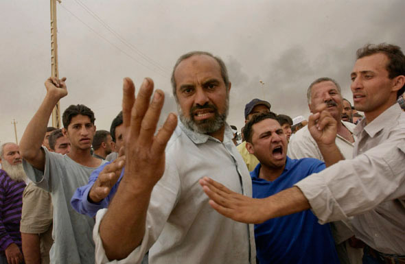 Angry residents of Zafrania confront U.S. soldiers guarding an ammunition stockpile after an accident launched a missile that killed people in nearby houses. 