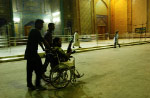 A wheelchair-bound member of the Mehdi Militia takes a nighttime tour of the outer walls of the Imam Ali shrine. The shrine was at the center of a three-week American seige of the old city of Najaf where Mehdi Militia fighters loyal to Muqtada al-Sadr staged a rebellion against the Iraqi government and American military occupation.