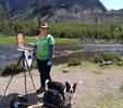 The artist, S'zanne Reynolds, painting in Yellowstone with  canine companion, John Singer Sargent.