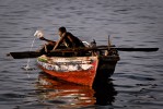 Fisherman taking water out of his leaking boat in Cap-Haitian.