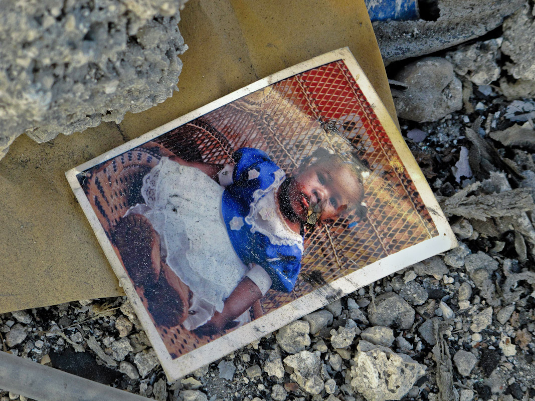 A photograph of a girl near a pile of rubble.