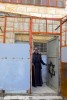 Palestinian man standing in front of his home where a cage was recently built around it to protect his family from Israeli settlers throwing rotten food and stones at them.  The settlers have also graffitied his door with a Jewish star.