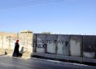 Palestinian woman walks by graffiti in the palestinian side of Hebron (H2) telling Israeli settlers that they will pay in the end.