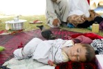 Refugee baby lying outside the family's tent as a crow stands by at the Swabi IDP camp in Swabi, Pakistan on May 2009.  There are now 1.5 million displaced people in Pakistan's North West.  
