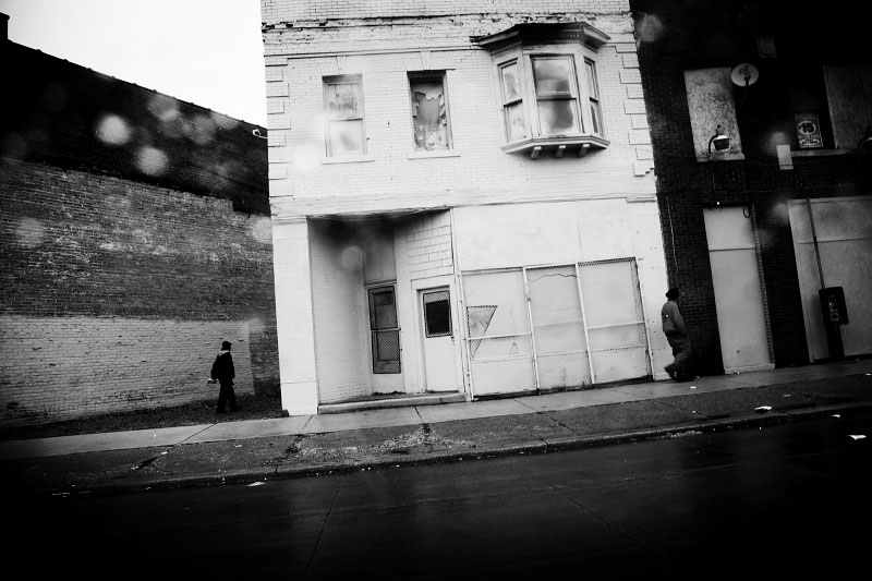 Detroit men walk in the neighborhood where abandoned or empty houses are quite often seen and drug is dealt.