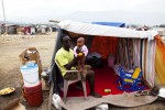 At Pone Rouge refugee camp, 24 year old Haitian quake IDP Jean Renald Celestin holds his 5 month old baby Sarah at his tent where his wife also lives. He lost his brother and sister due to the January 12th earthquake, and Christella lost her aunt.