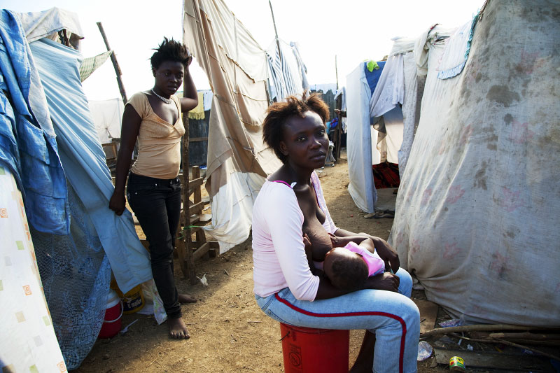 At Pont-Rouge refugee camp, 26 year old Haitian earthquake survivor Dleula Antoine gives mother milk to her 6 month old baby Florige next to her tent, as her quake survivor friend stays nearby. 