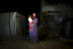26 years old mother Heba Fareed Abu Jama'a and her daughter Moha Hussein, 2 years and 3 months, pose at their destroyed house due to Israeli attack during the summer's 50 day war between Hamas. Since there is no space to move, or too expensive to do so, they have to live at a tent next to the house, with 8 other persons.Al-Zana'a in Khan Yunis, Gaza, Oct 08, 2014.