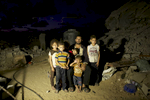 Adil Mohammed Abu Samhan, 42, and his children pose in front their destroyed home in Khan Yunis by Israeli airstrike and bulldozers during the summer’s 50-day war between Israel and Hamas. They have to still live at the site, since there is no place else for them to move, or too expensive for the rent after the war. Al-Zana'a in Khan Yunis, Gaza. Oct/03/ 2014