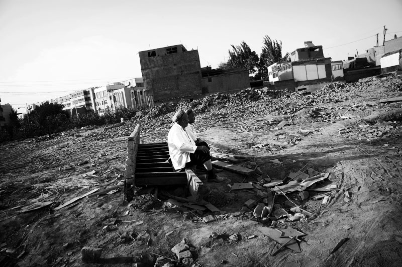 Two Uighur men are staying at their demolished and flattened community due to the Chinese modernization projects or Chinesefication, though the government insists the main reason is security of houses -- especially resistance to earthquake, in Kashgar, Xinjiang.