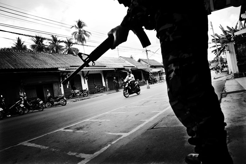 Thai soldiers take the cover near a checkpoint, while a motorbike passes through in Rueso in South Thailand where the majority is Muslims and they are often in poverty compared to Thai Buddhists. Due to the strong Buddhism identity of Thailand, many southern Muslims feel themselves in limbo and a certain number of the people look for the independence or joining together with Malaysia. Unfortunately the bloody separate insurgency continues. April 12 2008, Rueso, Thailand.
