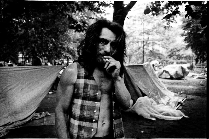 A homeless man smokes cigarette in Tompkins Sq Park, while the so-called tent city, as symbol of resistance, has been established in the park. New York, May 29, 1991.