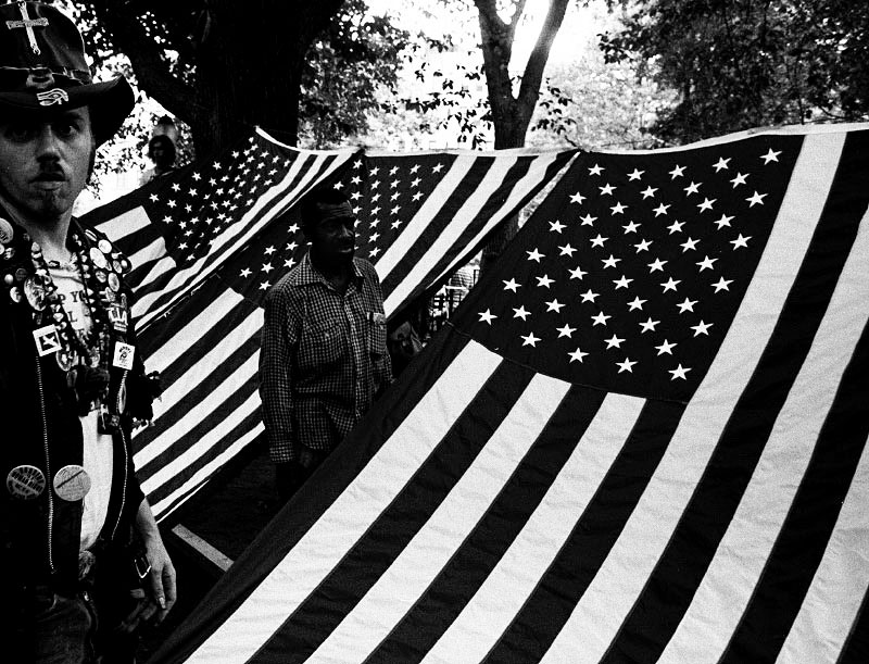 In Tompkins Sq Park, homeless people and supporters camp out under Americanflags to highlight homelessness. New York Aug 1989.