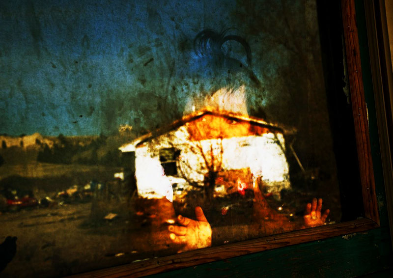 Serset, two year old lakota toddler, looks onto outside, as the desolate town of Manderson is reflected on the window. 