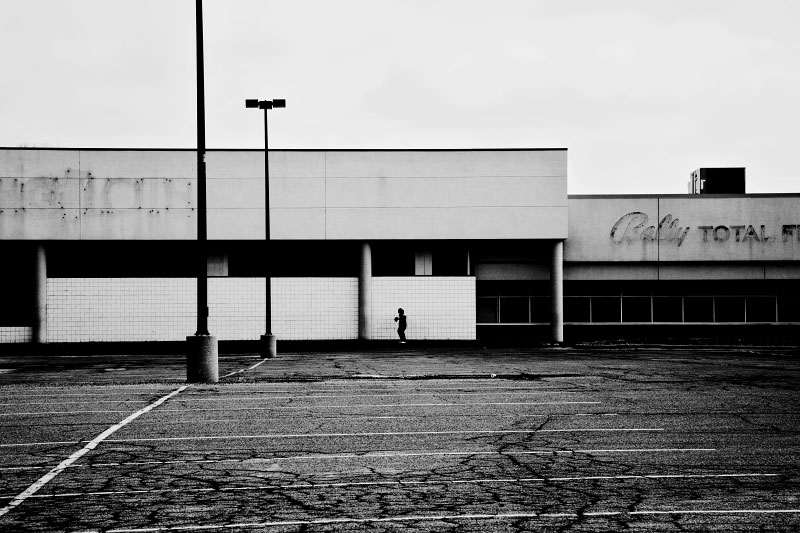 A man walks in front of a closed down store in a Detroit shopping mall, though some of the stores are still open, the parking lot is deserted. March 2008.