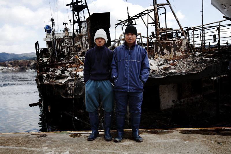 Tsunami survivors, Indonesian foreign students for the Japanese fishing industry, stand in front of a destroyed ship, Kesennuma, Miyagi.